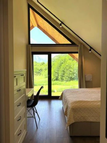 Cozy attic bedroom with large window and forest view