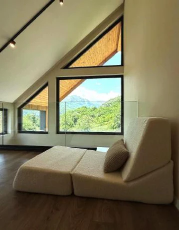 Modern attic lounge with triangular windows and mountain view